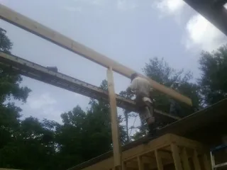 Carpenter setting a ridge beam over a new addition frame — Ice Dam Removal by Roofing Brothers in Turners Station