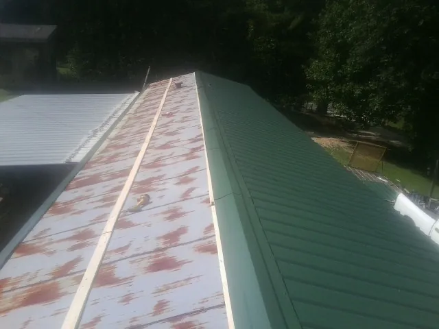 Old rusted panels beside newly installed green metal roofing — Wind Damage Roof Repair by Roofing Brothers in Turners Station