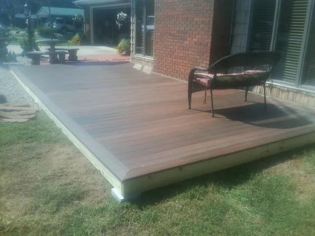 New wood deck and wicker chair beside a brick house in Turners Station
