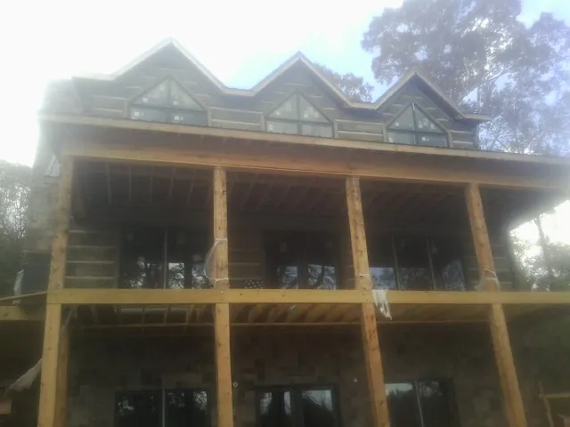 Dormers and porch framing on a large log home under construction — Roof Coating work by our crew in Turners Station