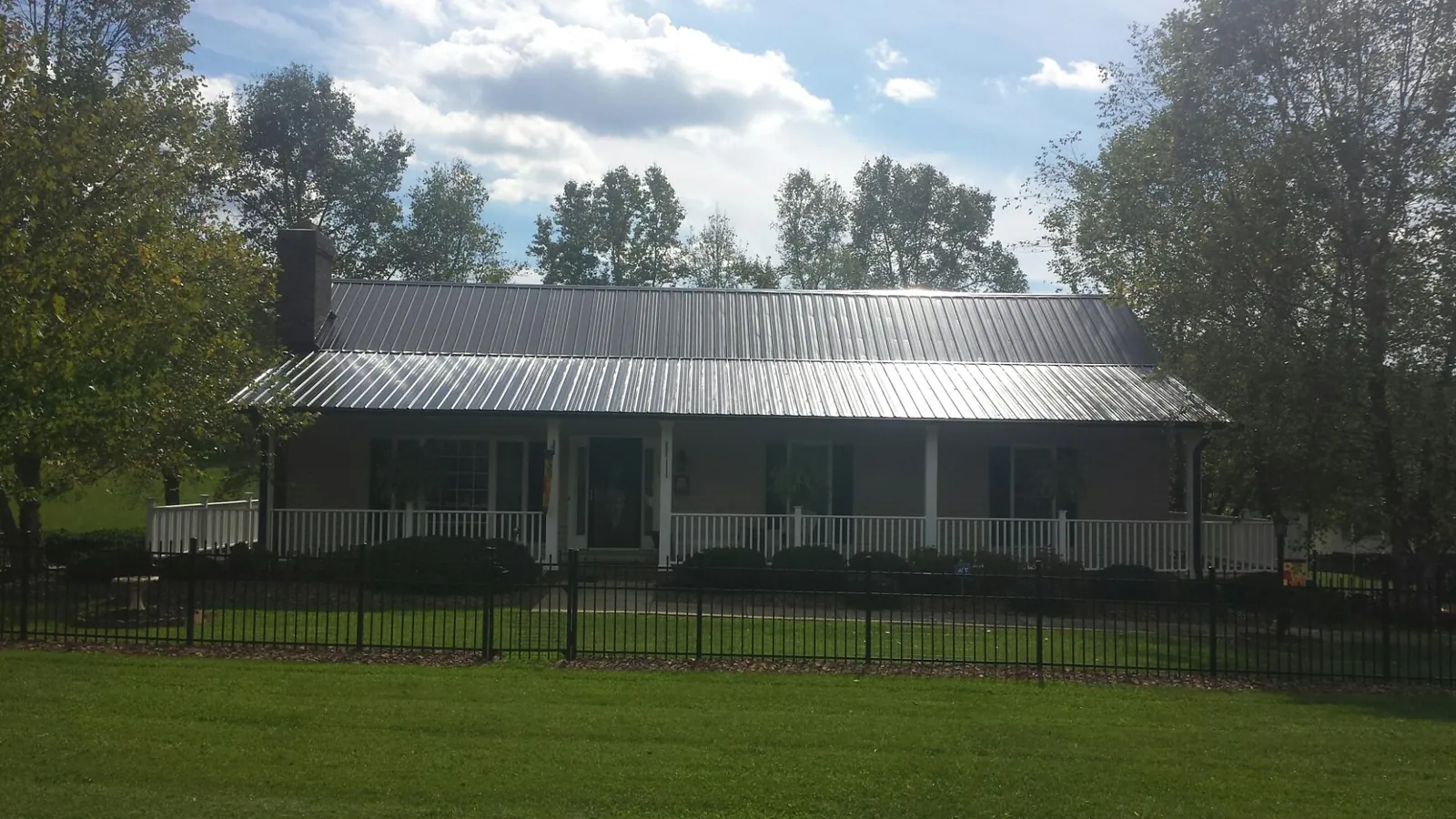 Gray metal roof on a brick ranch with a full width front porch — Gutter Guard Installation work by our crew in Turners Station