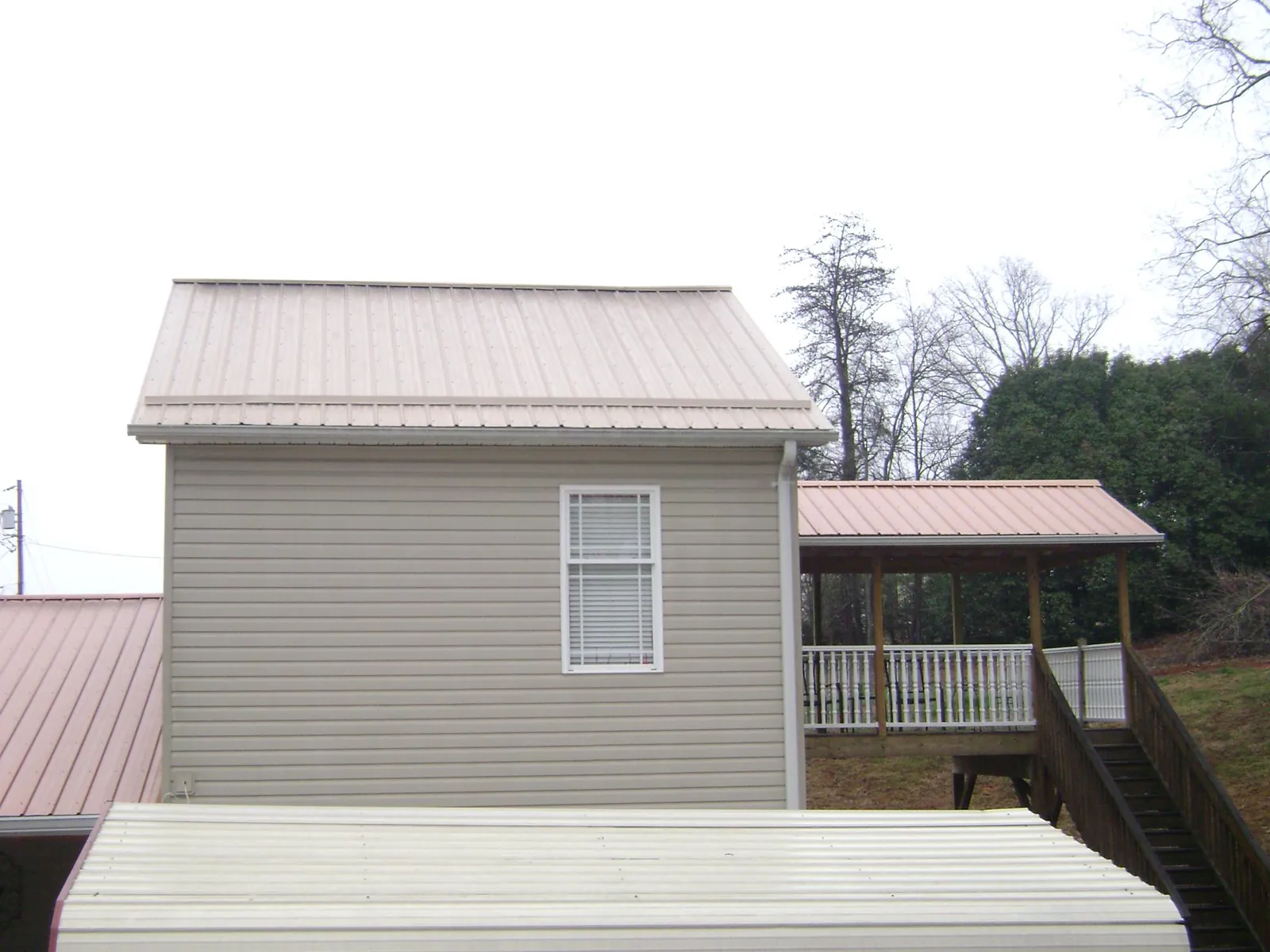 Tan metal roofs on a two story addition and attached porch, from a Roof Replacement job in Turners Station