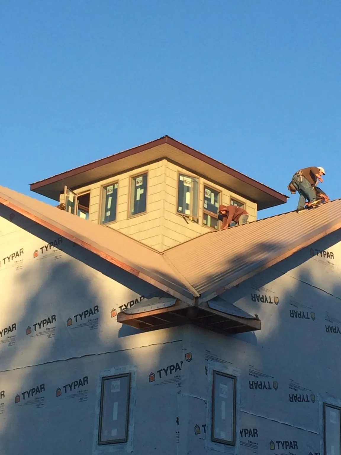 Roofers working around a rooftop cupola on a new metal roof at sunset — Roof Waterproofing in Turners Station by Roofing Brothers